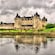 A castle with lush grounds overlooking the water